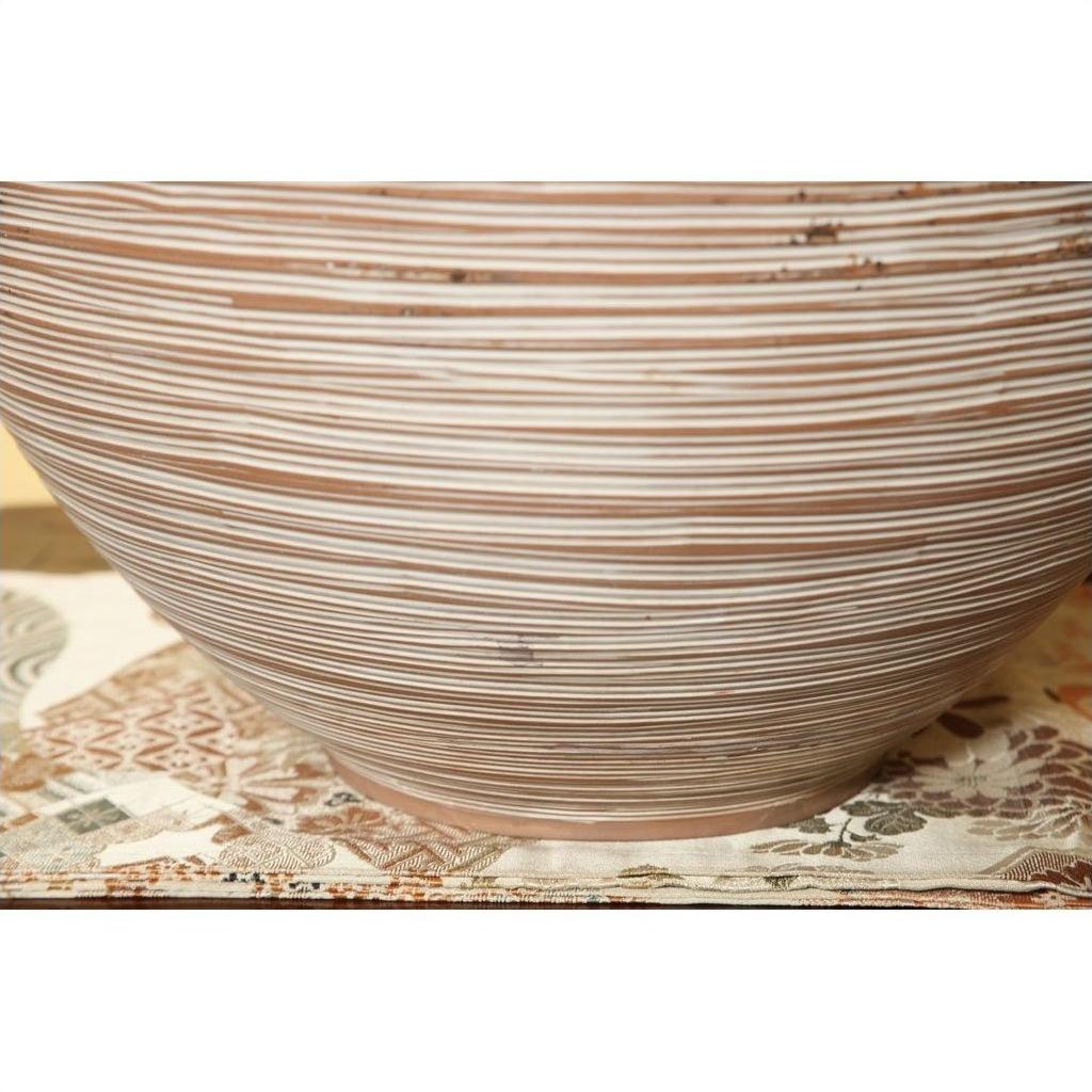 Brown and white ceramic vase with thin stripes on patterned cloth.