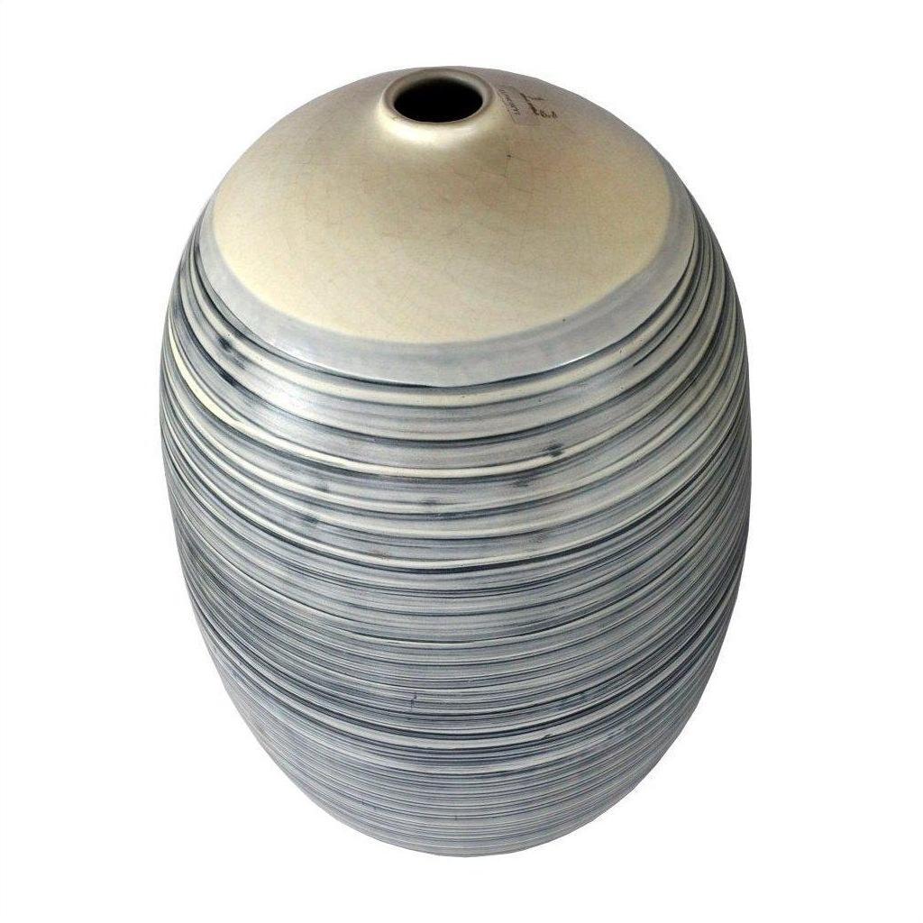 Close-up of large white ceramic vase with blue-gray stripes and a crackled finish.