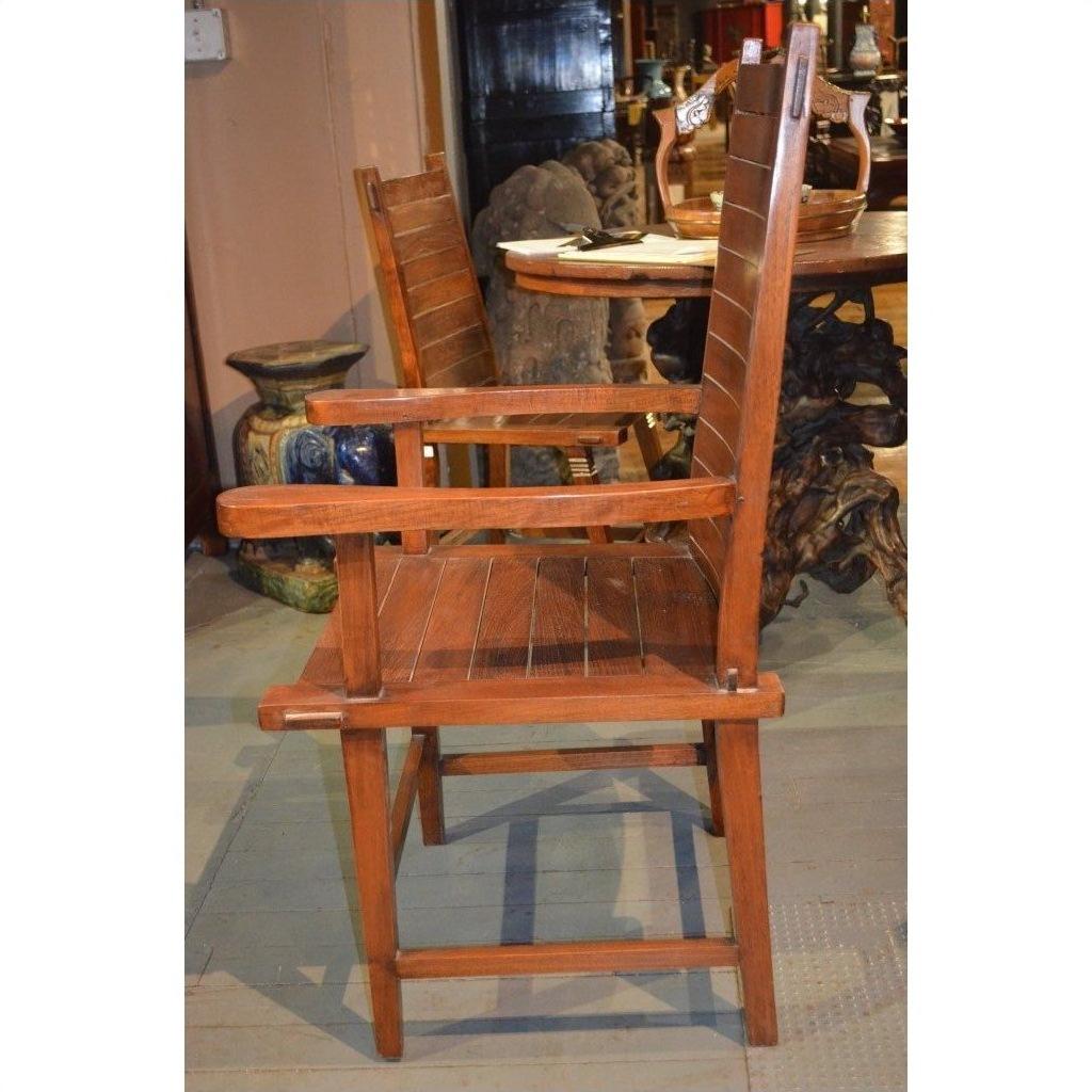 Brown wooden Arts &amp; Crafts style chair with slatted back and seat, side view indoors next to a round table.
