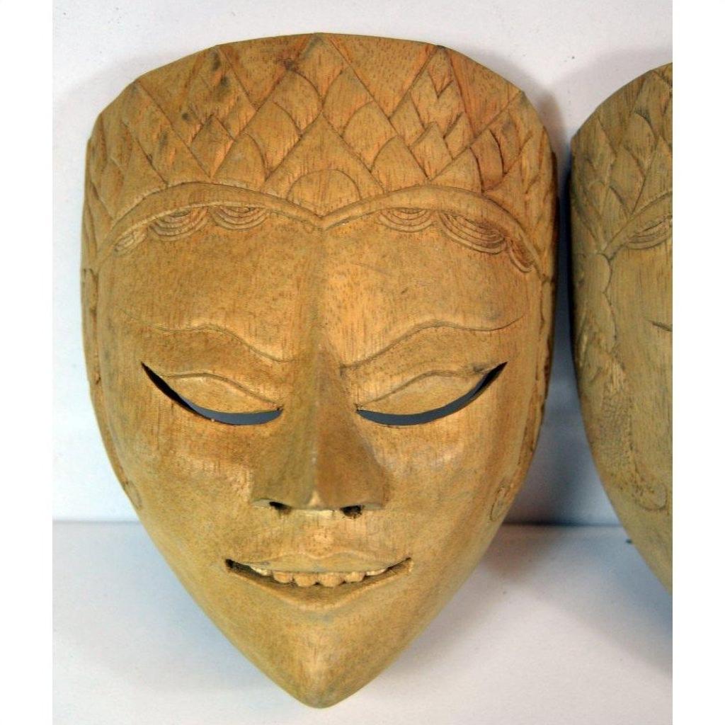 Close-up of brown carved wood Balinese dancing mask with closed eyes, subtle smile, ornate forehead patterns.
