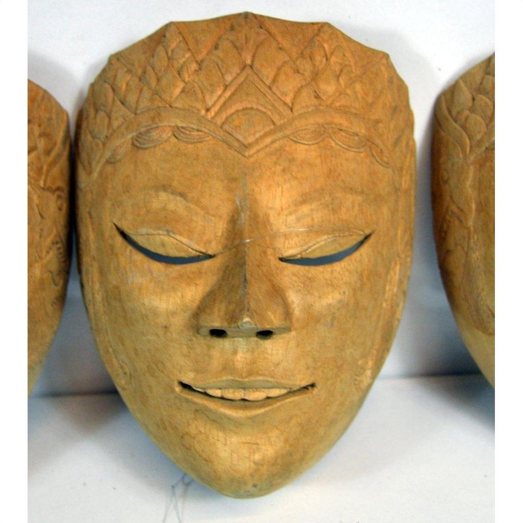 Close-up of a carved wood Balinese dancing mask with closed eyes, delicate etched patterns, and a serene expression.