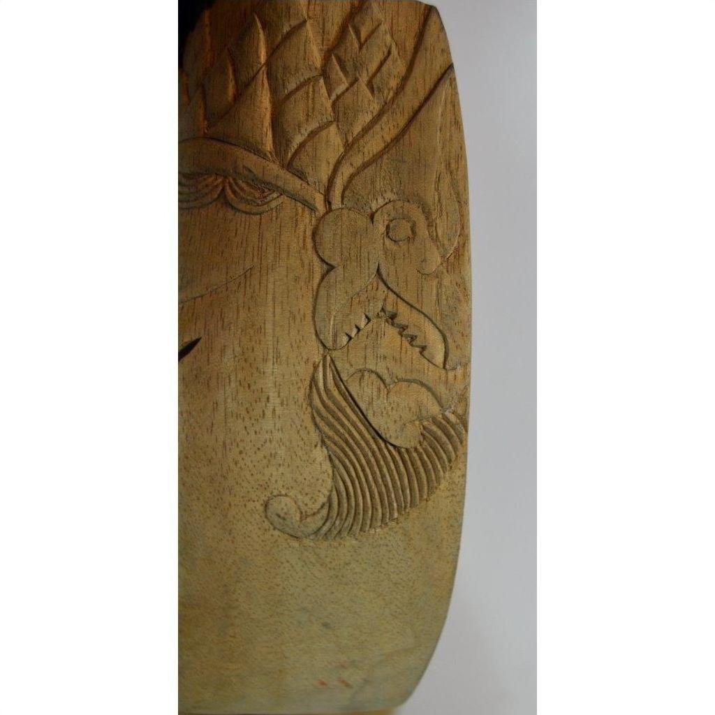 Close-up of a light brown carved Balinese mask with intricate patterns, close-up view.