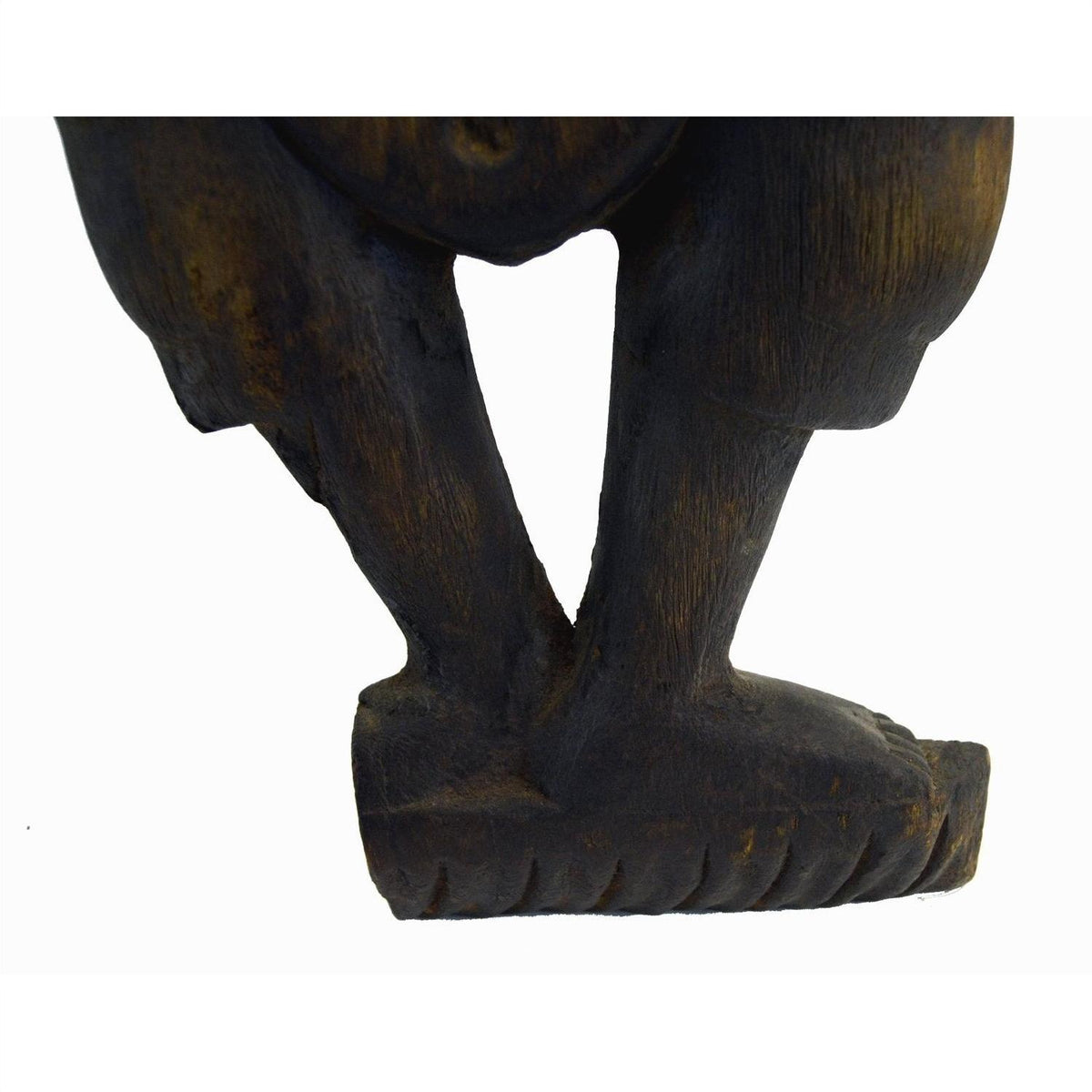 Close-up of a brown hand carved wood Balinese temple dancer sculpture, showing both legs and feet on white background.