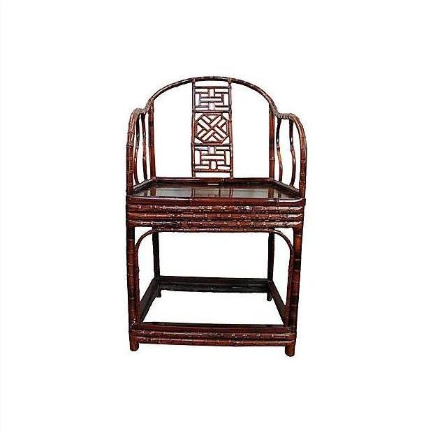 Brown bamboo horseshoe chair with curved backrest, geometric cutout, armrests, and rectangular seat.