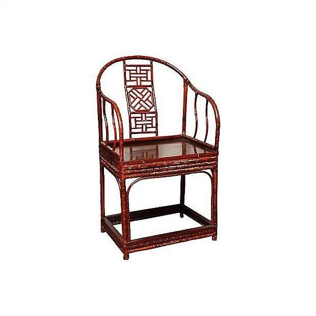 Brown bamboo horseshoe chair with curved back, geometric lattice design, and slender arms and legs, indoor setting.