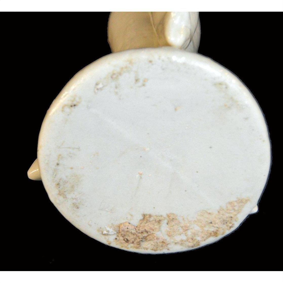 Close-up of the base of a white Blanc de Chine porcelain candle holder with dolphins, showing edge wear and discoloration.