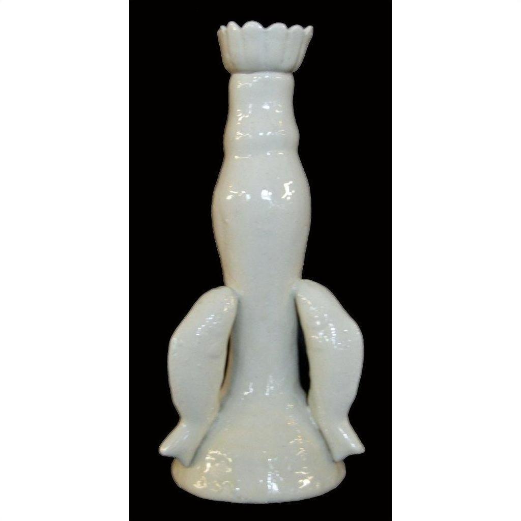 White porcelain candle holder with dolphin figures on a flared base, displayed against a black background.