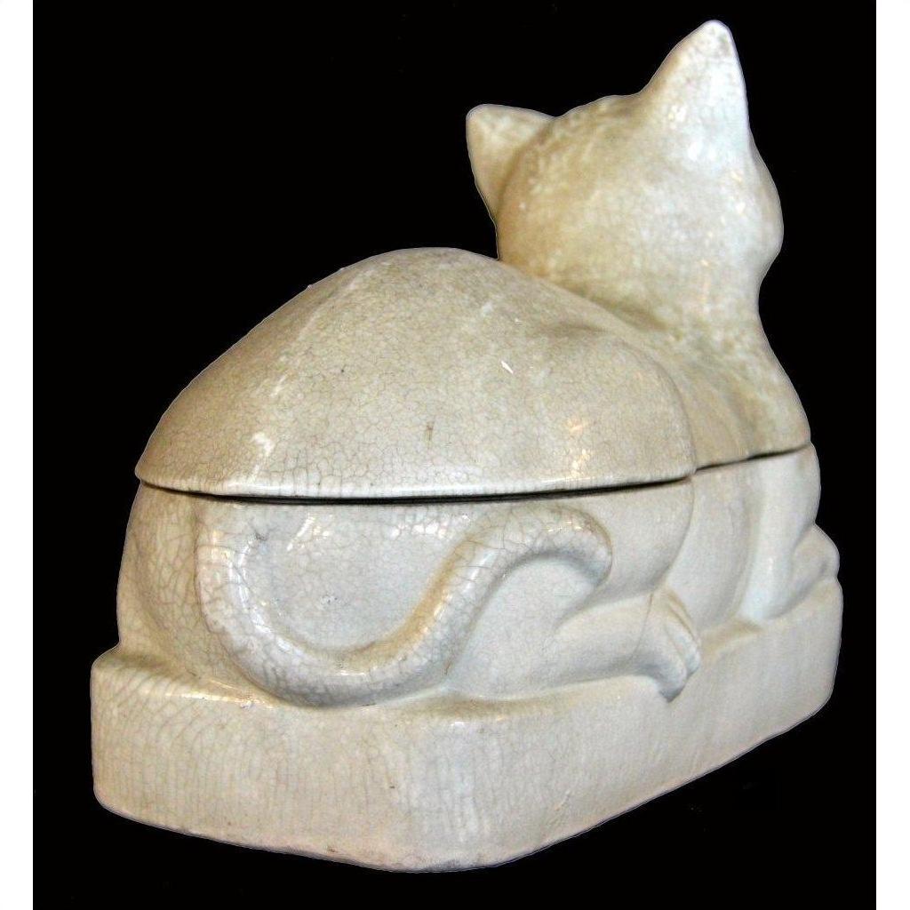 Cream-colored porcelain cat with crackled glaze, viewed from back and side against black background.