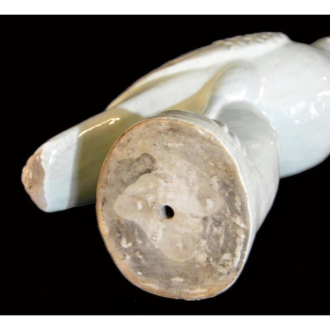 White porcelain dove figurine lying on its side with unglazed round base and small center hole visible.