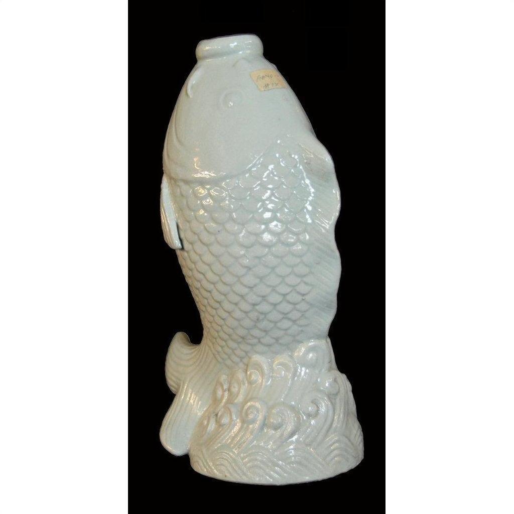 White porcelain fish with detailed scales, rising from stylized waves, displayed on a black background.