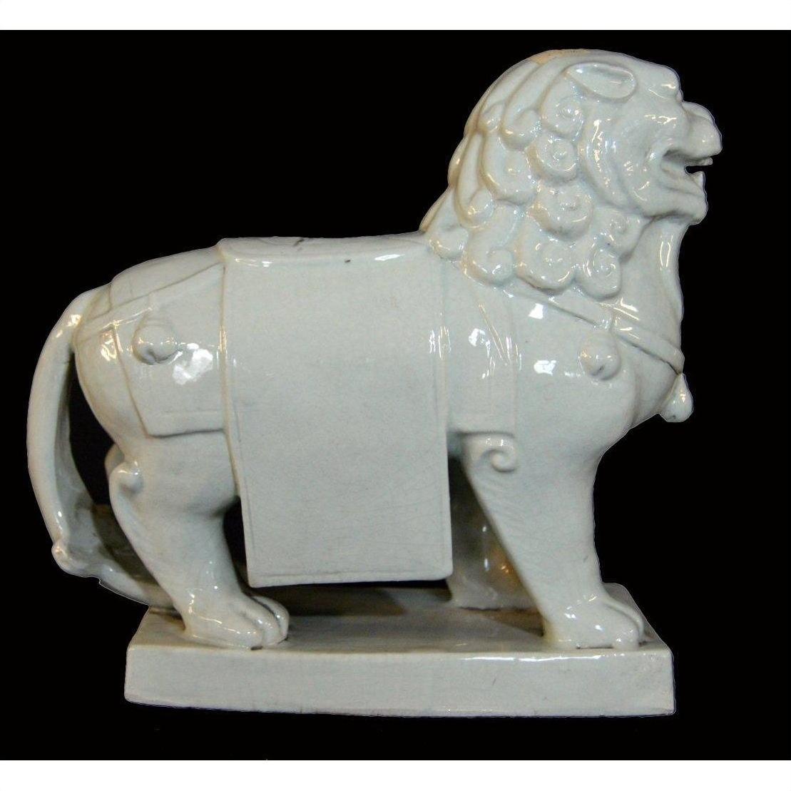 White porcelain Foo-Dog with stylized mane and draped cloth on rectangular base, close-up.
