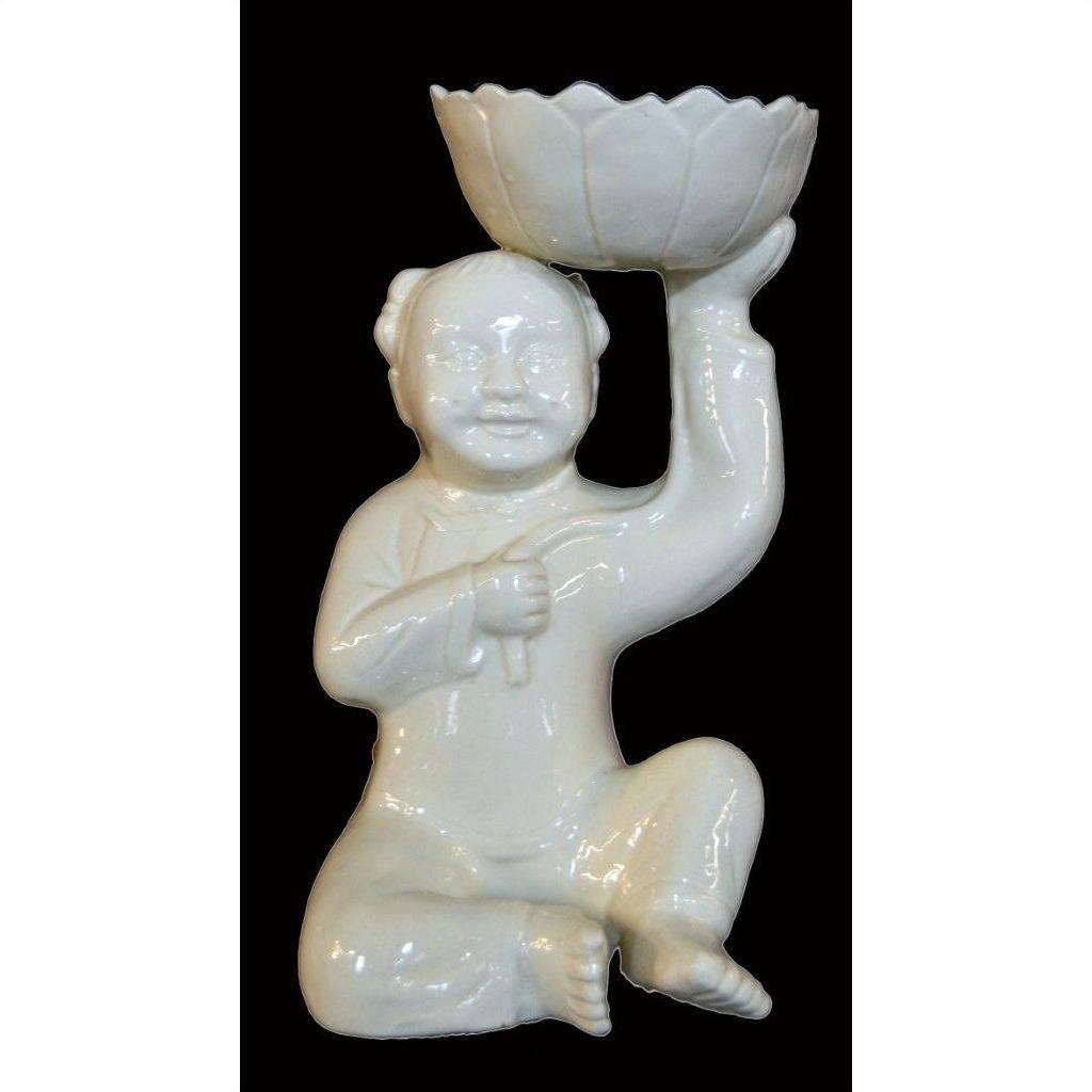 White porcelain monk figurine kneeling and holding bowl aloft, set against a black background.