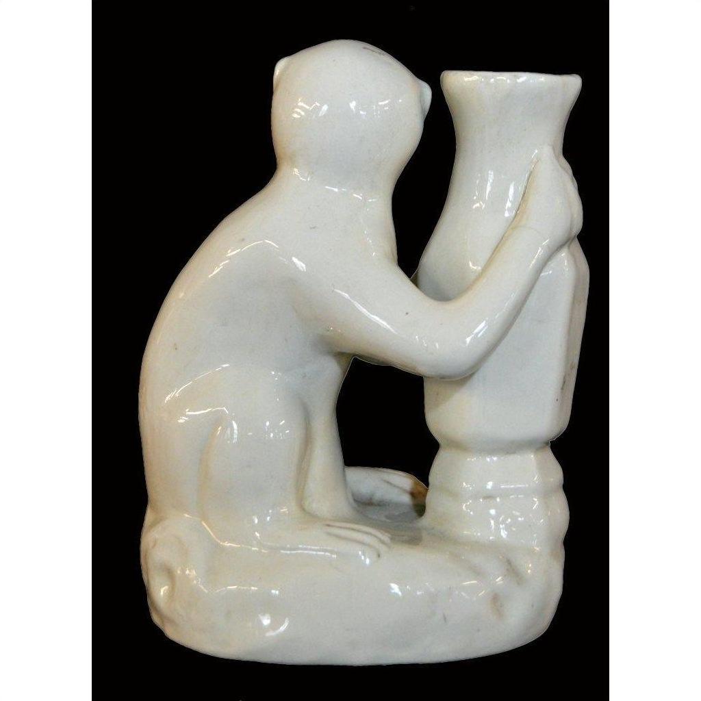 White porcelain monkey figurine hugging tall vase, close-up against dramatic black background.