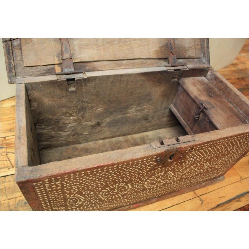 Open wooden blanket chest with white bone inlay displayed on a wooden floor, empty interior visible.