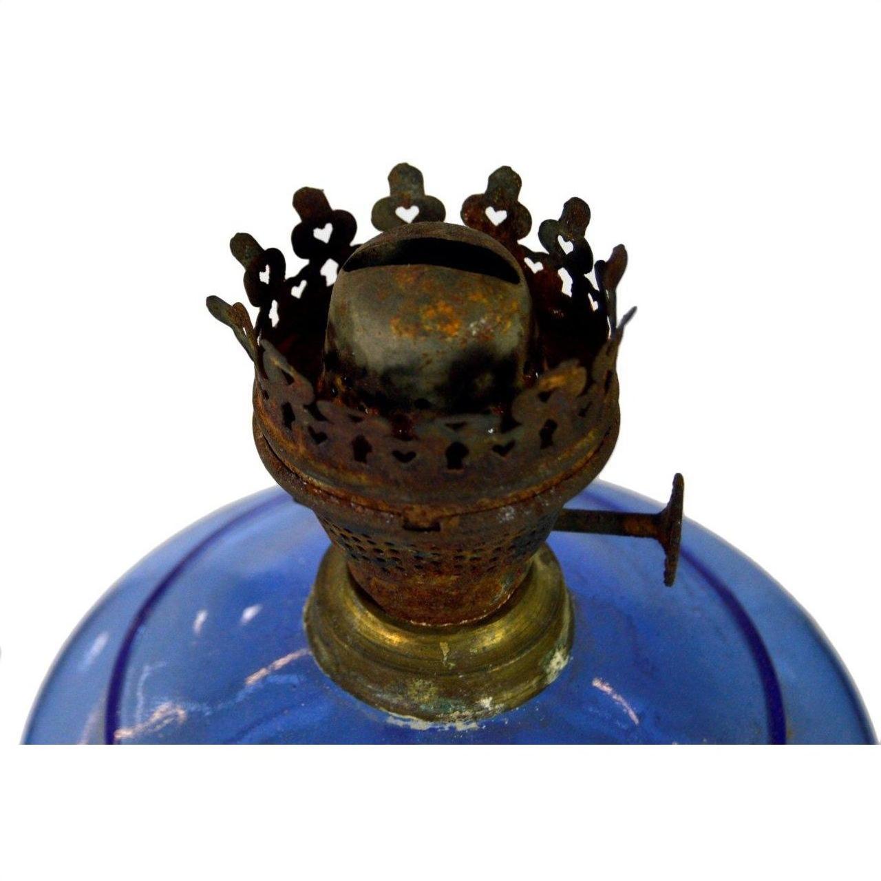 Close-up of a rusty burner on an antique blue glass oil lamp in very good condition, set against a white background.