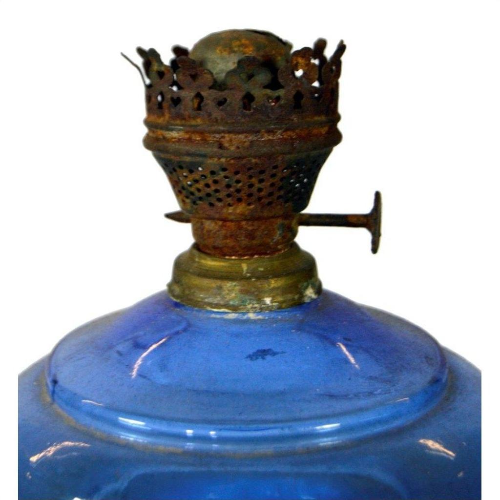 Close-up of antique blue glass oil lamp with rusty metal burner, in very good condition on plain white background.