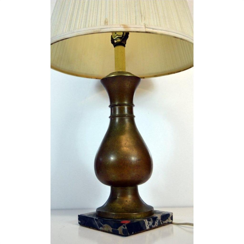 Beige pleated shade brass lamp with a black marble base, close-up against plain background.