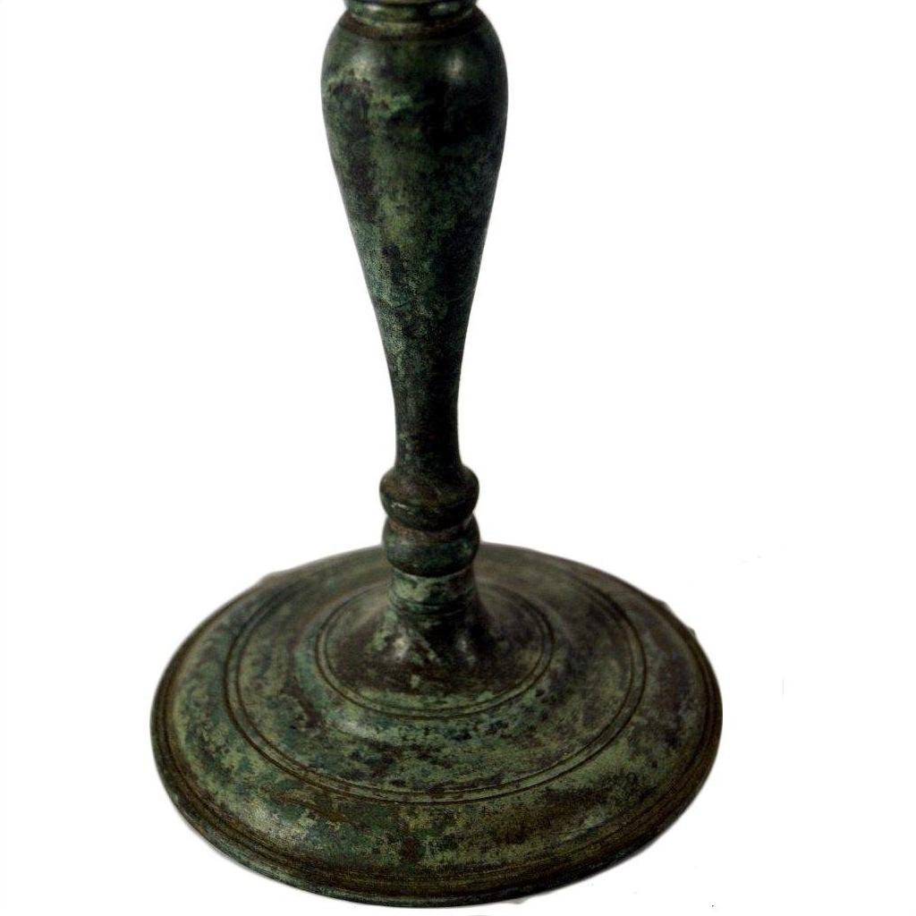 Close-up of greenish bronze candelabra with slender stem, lost wax casted.
