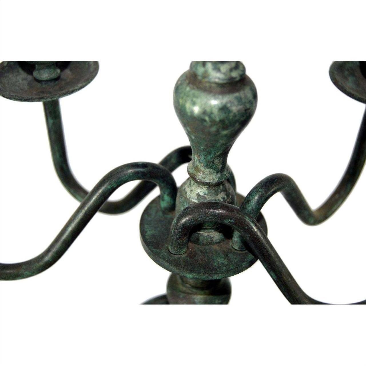 Close-up of bronze candelabra with three curved arms, lost wax casted, on a plain white background.