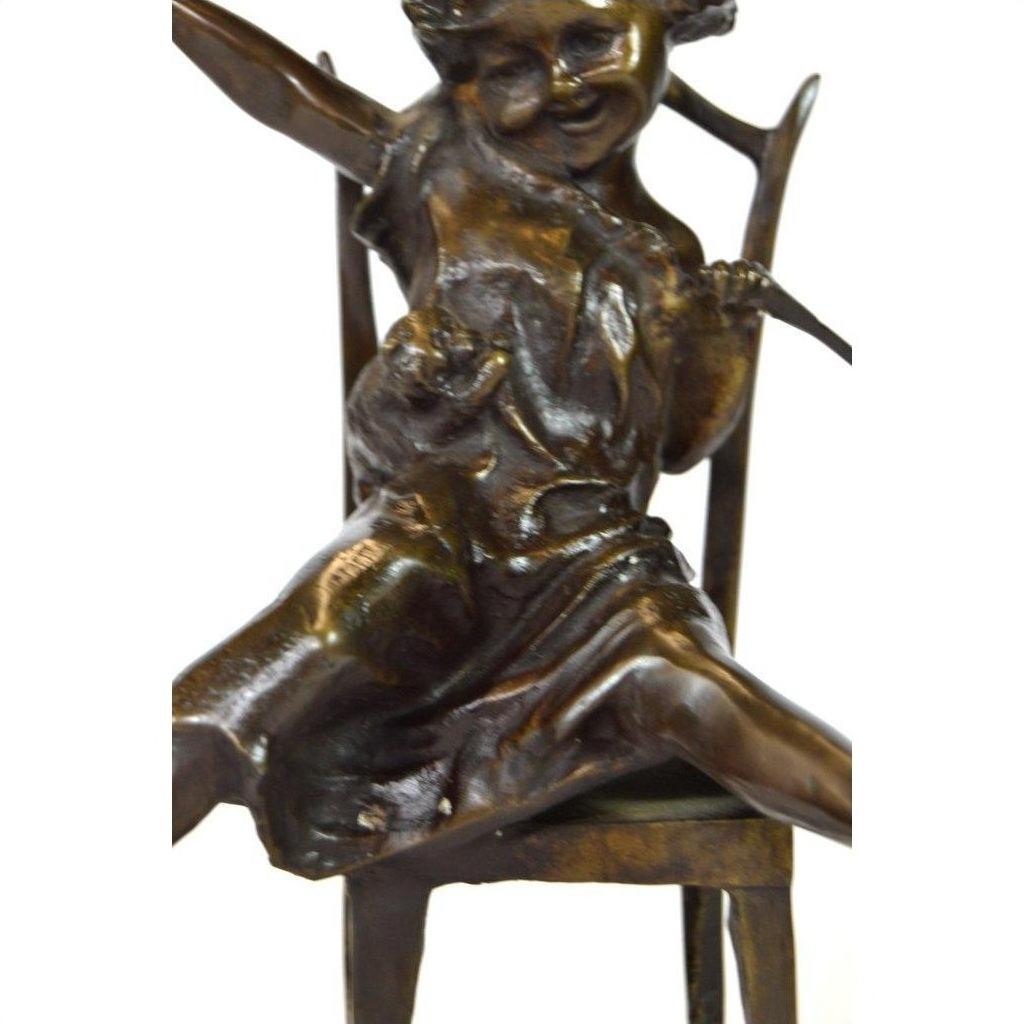 Bronze child doll sculpture smiling, sitting on chair with arms and legs extended, close-up view.