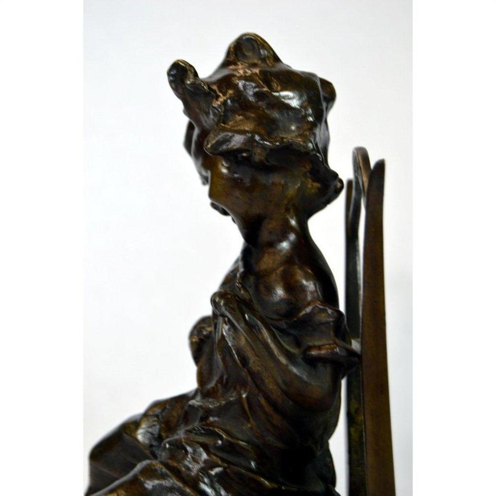 Bronze sculpture of abstract seated draped female figure in profile on plain background.