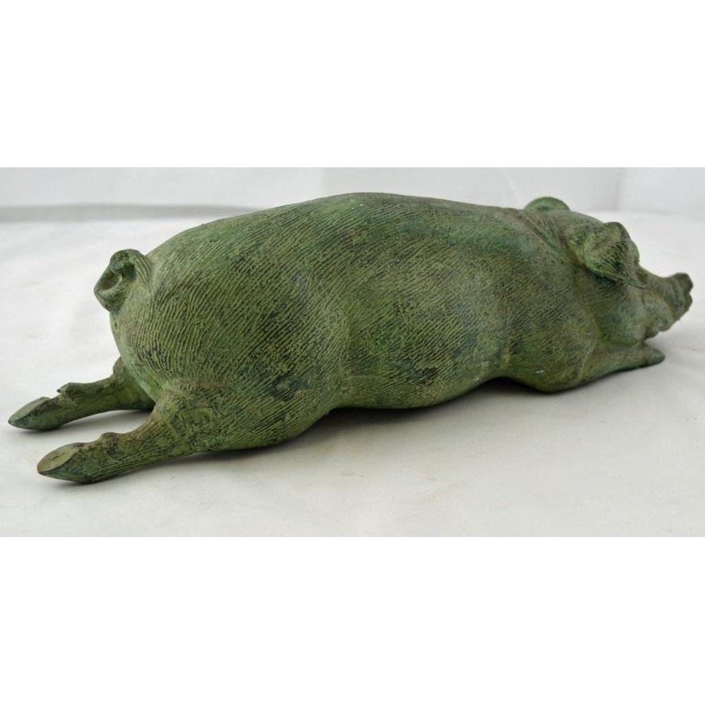 Greenish bronze pig sculpture lying flat with outstretched legs, ideal as tabletop decor, close-up view.