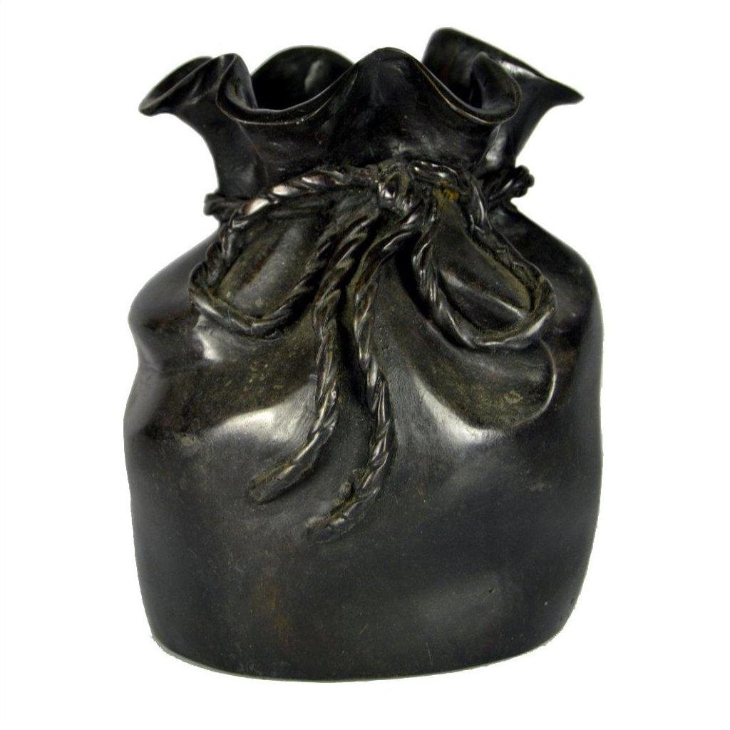 Close-up of a bronze ceramic vase shaped like a tied pouch with braided rope detailing on a tabletop.