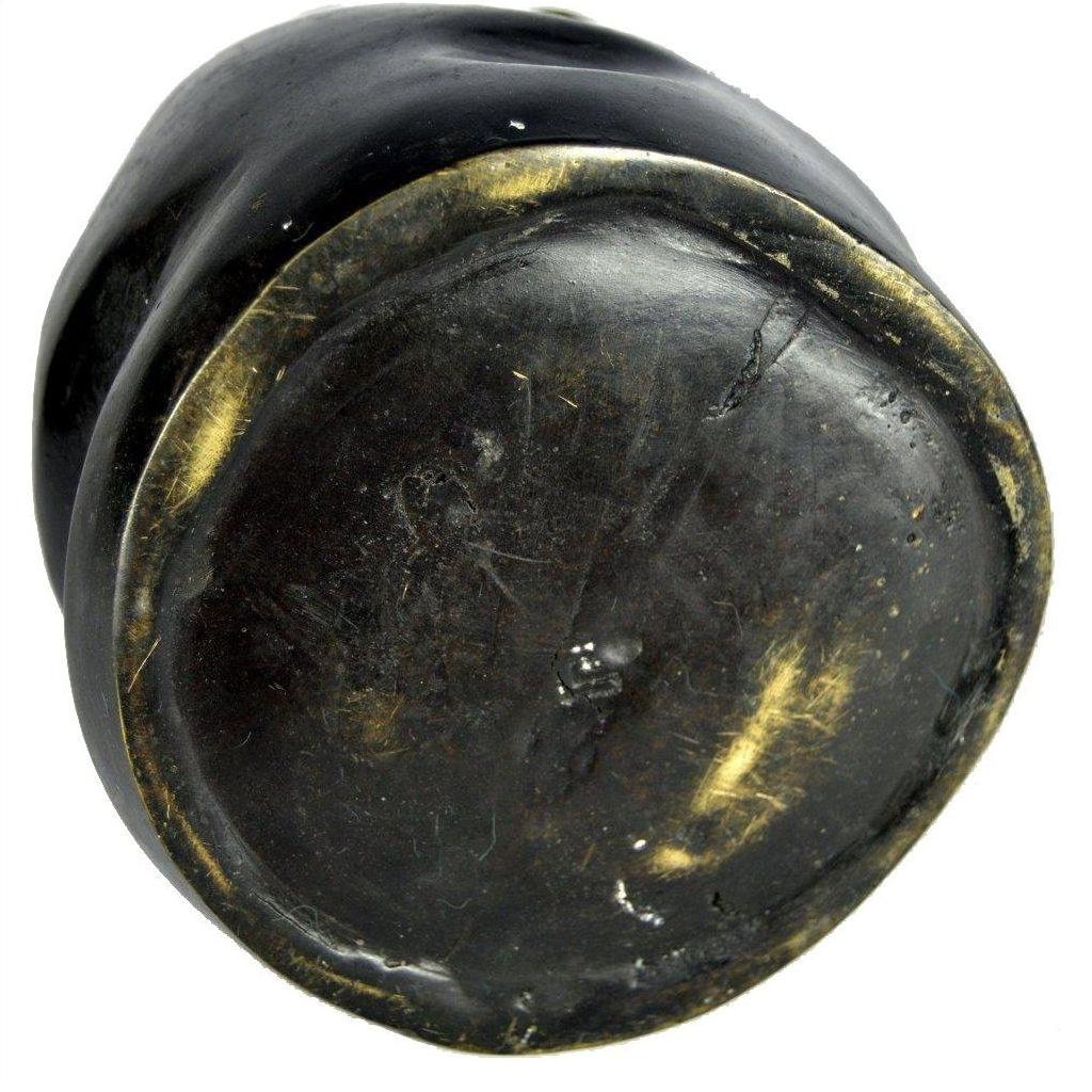 Close-up of bronze metal paperweight base with scuffs, gold-toned edges, showing worn, flat surface.
