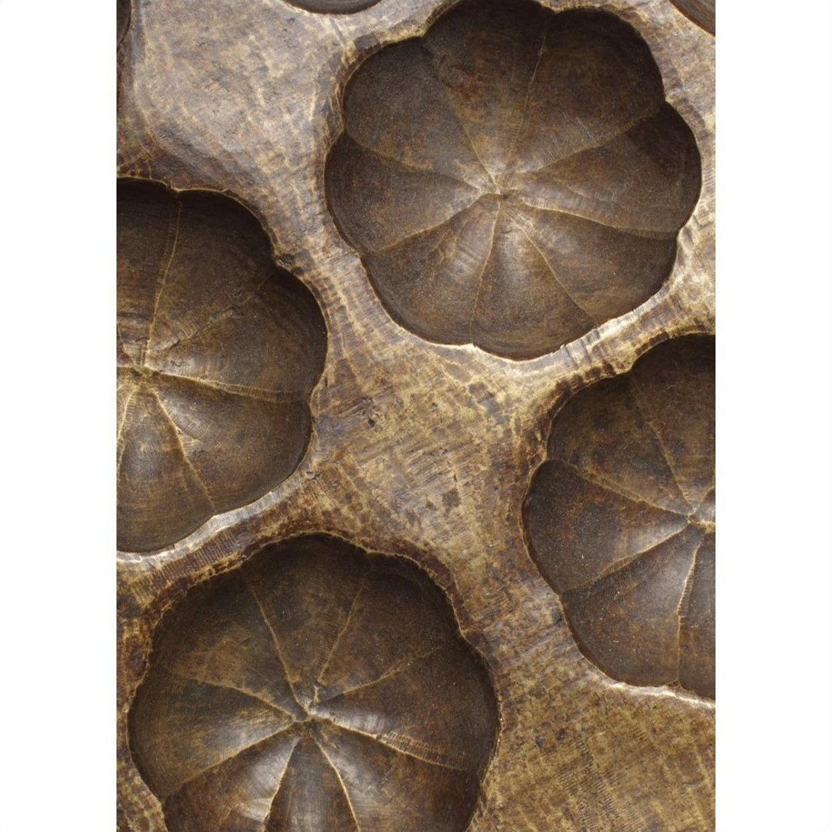 Close-up of bronze metal shell pan surface with carved circular, flower-like indents.