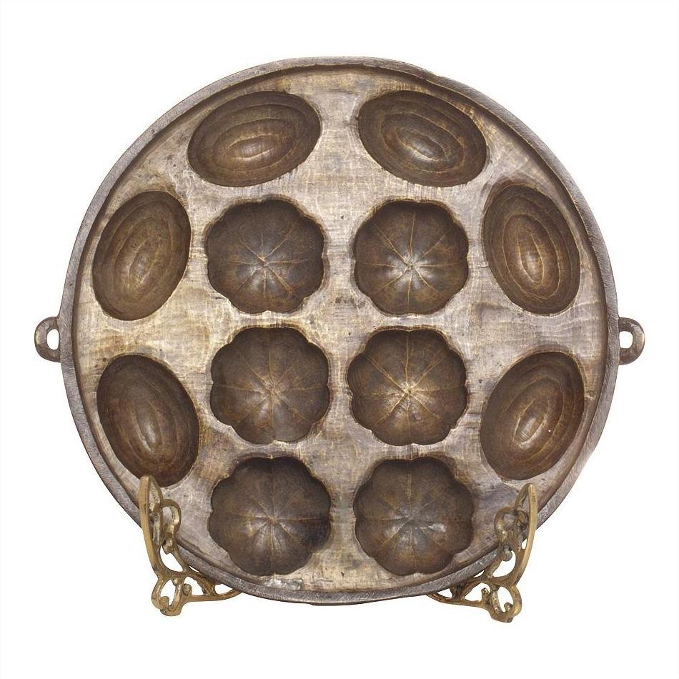 Round bronze shell pan mold with 12 flower and shell shapes, displayed on a metal stand.
