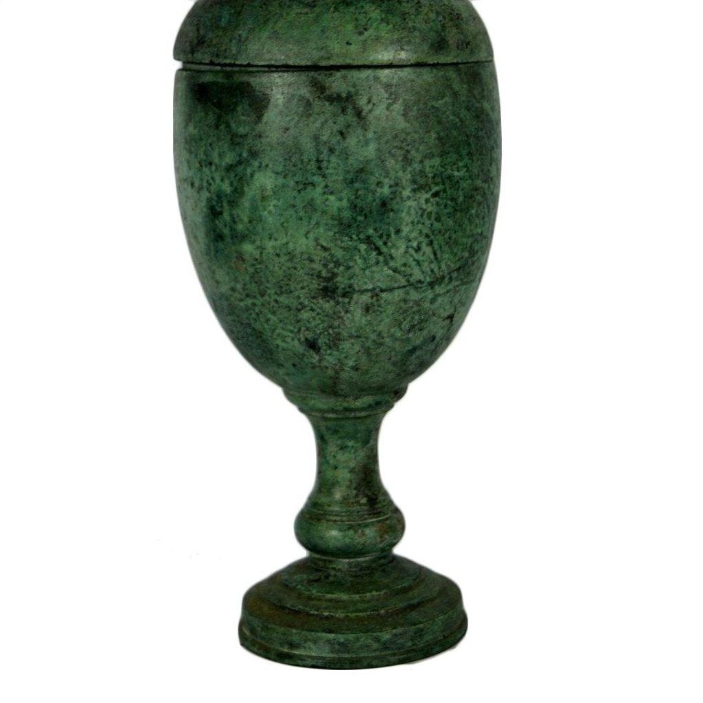 Green weathered bronze urn with lid, wide body, narrow stem, and round base on a white background.