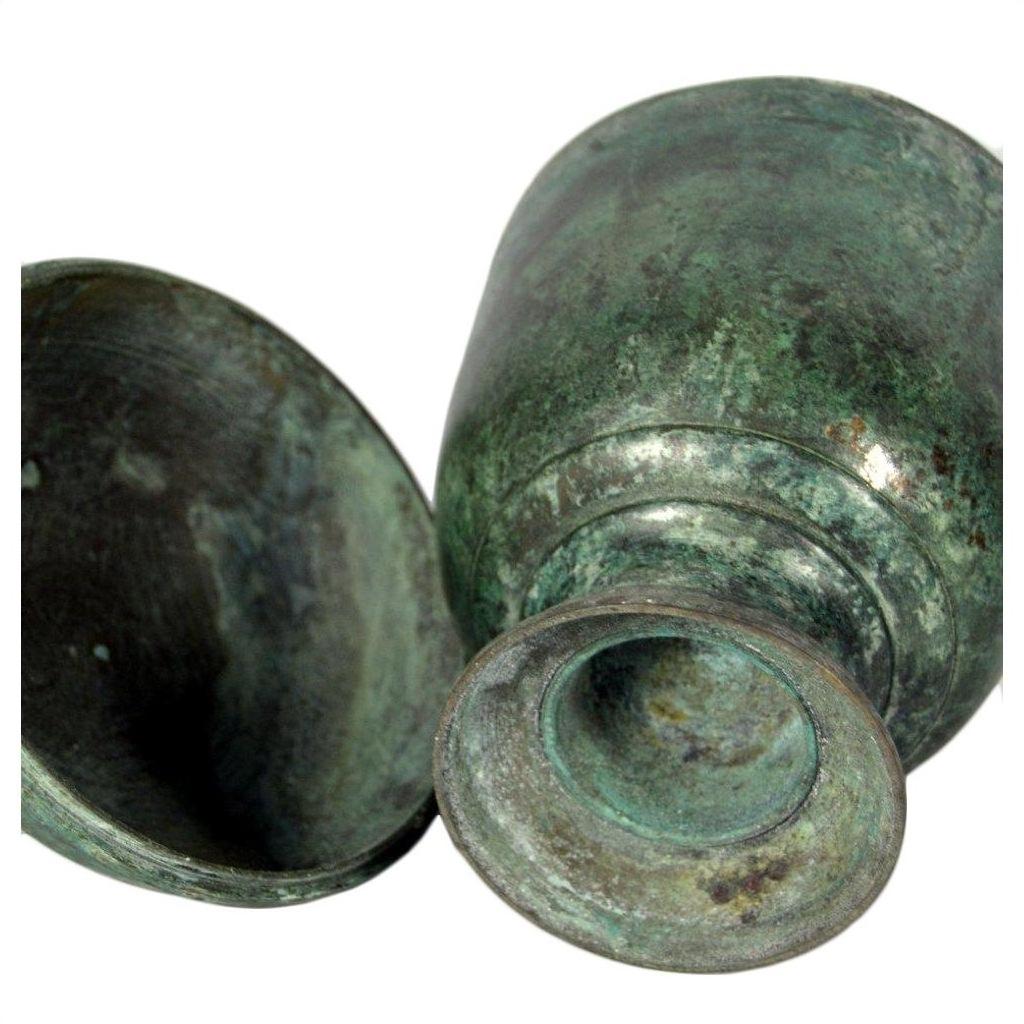 Green bronze urns with aged patina, lying on their sides, showing weathered surfaces.