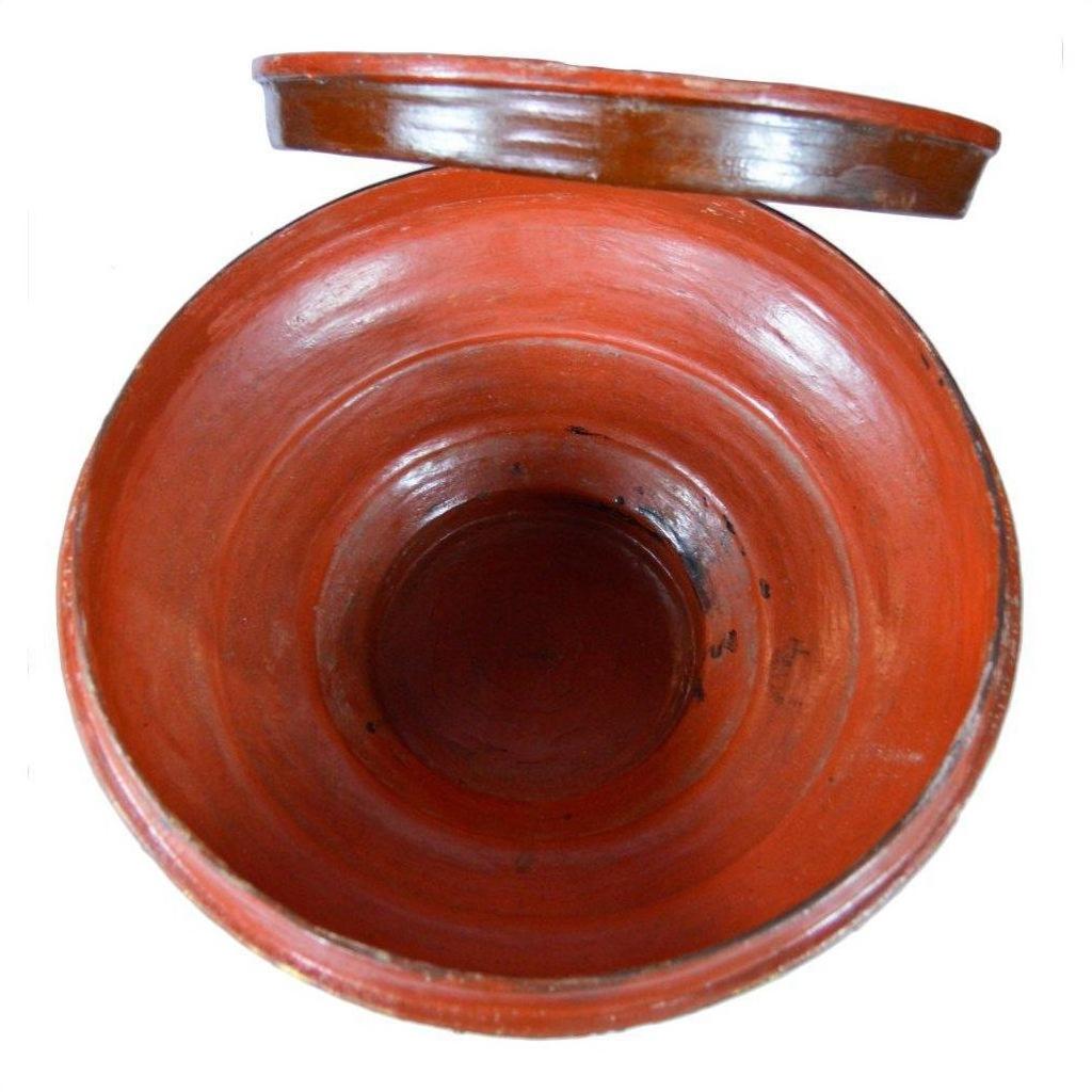 Red clay Burmese offering bowl with open lid, gilt accents, and smooth glazed interior, close-up.