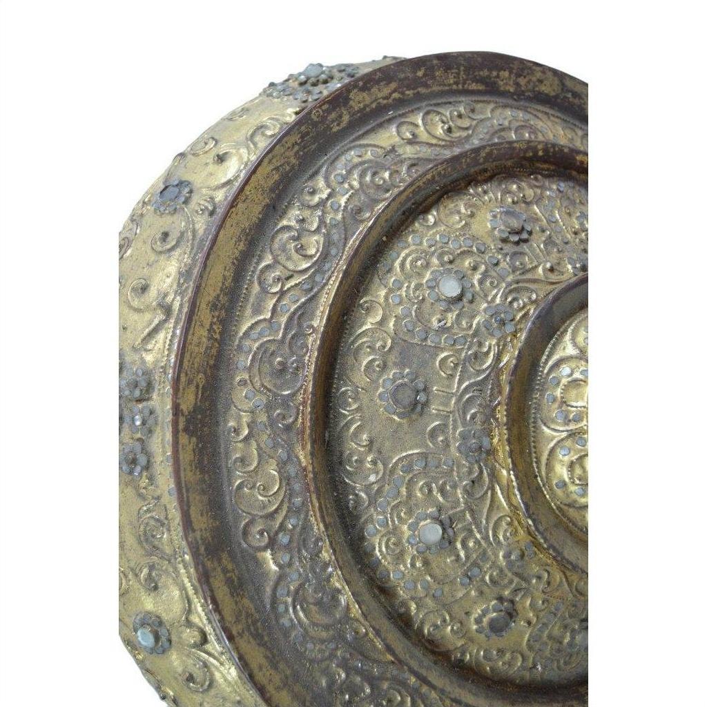 Close-up of a gold and bronze Burmese offering bowl with ornate floral patterns and embedded stones.