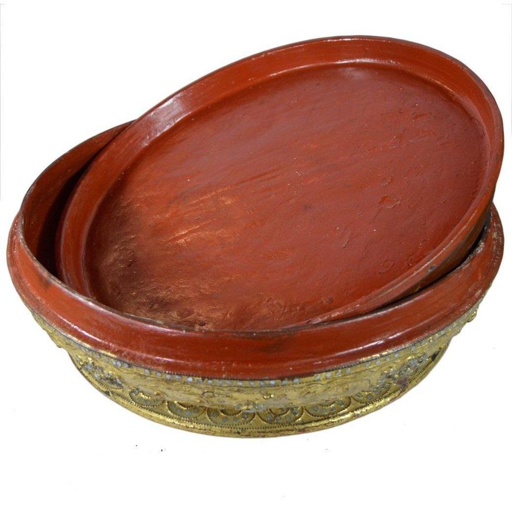 Close-up of two red lacquered Burmese offering bowls with ornate mica inlay and gilt bases, one stacked inside the other.