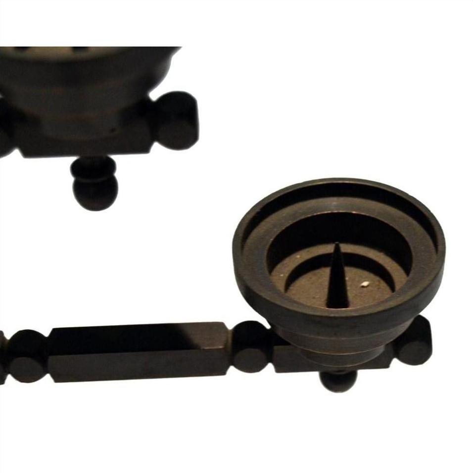 Close-up of a dark, geometric metal candle holder with circular and rectangular shapes on a white background.