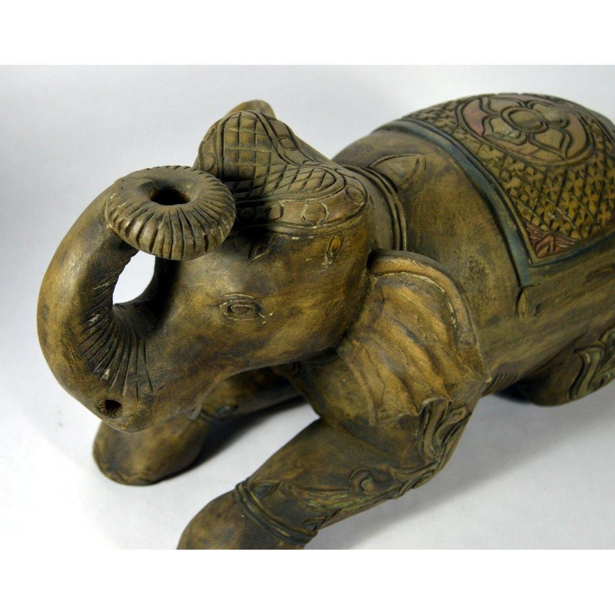 Close-up of hand-carved wooden elephant figurine with intricate patterns and raised trunk, very good condition.