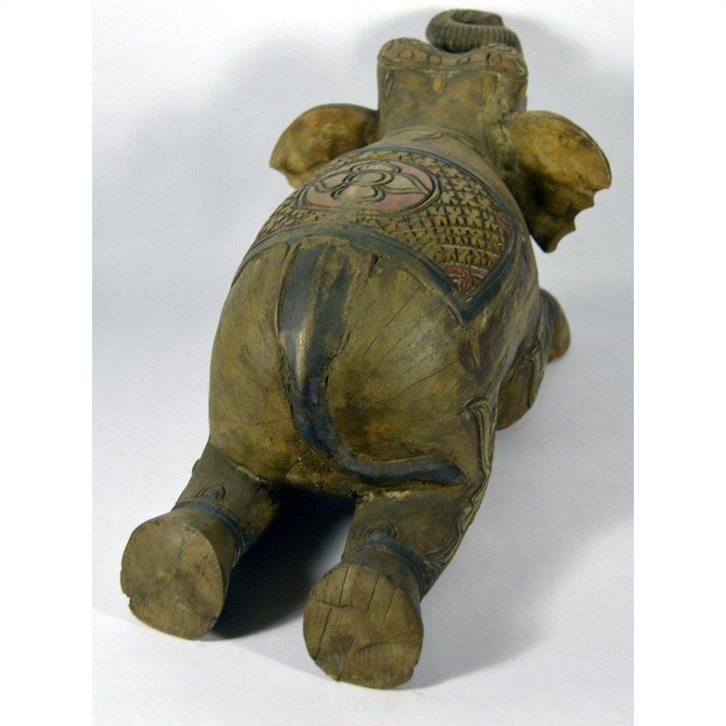 Painted wood elephant with carved patterns, belly-down, rear view, in good condition.