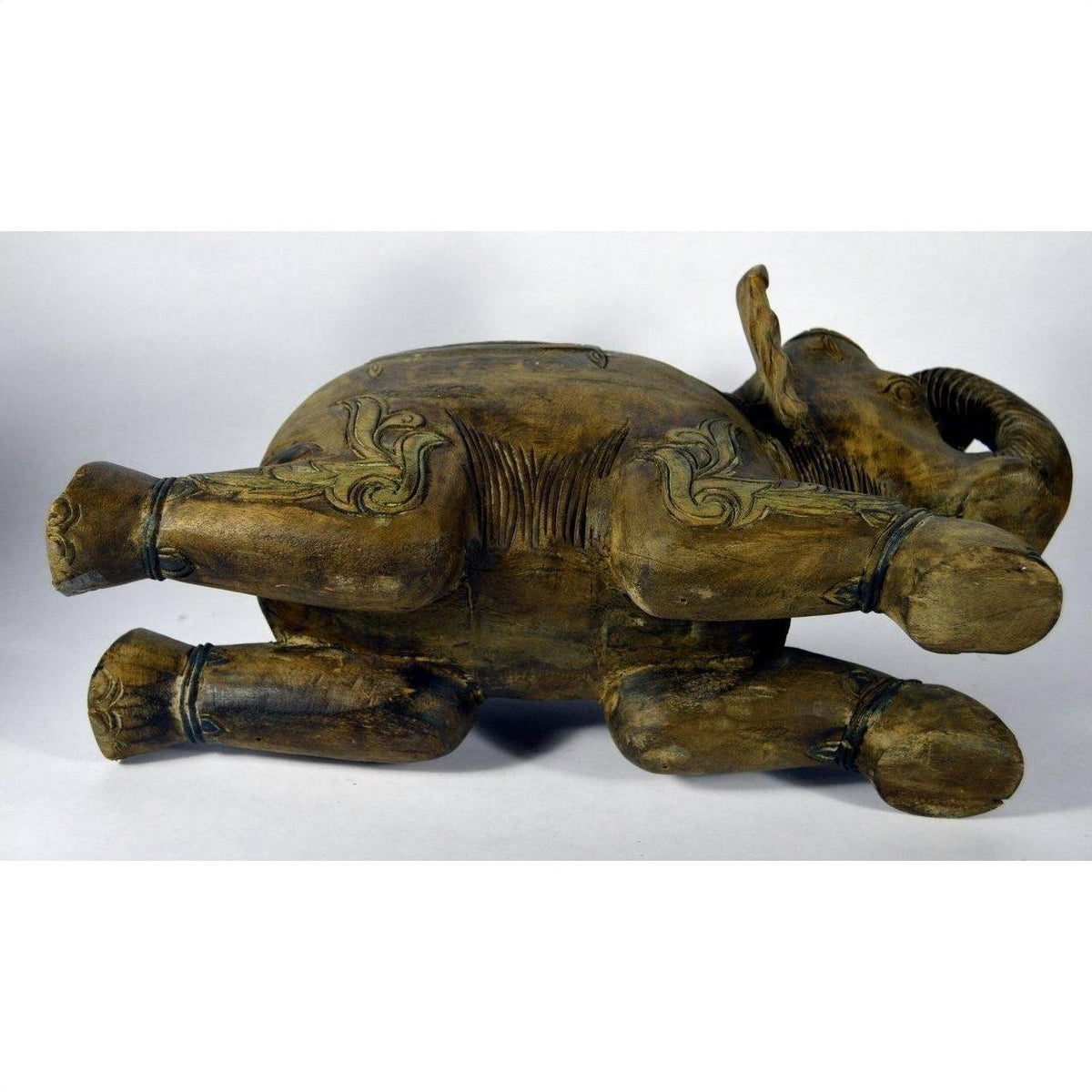 Brown wood elephant sculpture with intricate carvings, lying on its side, shown in good condition.