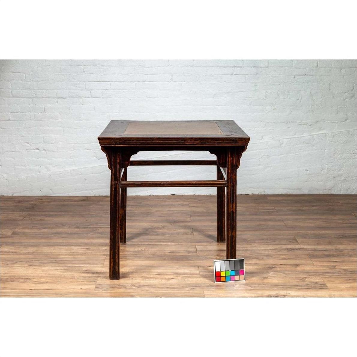 Brown elmwood center hall table with Ming Dynasty stone inset, Chinese 19th c., on wooden floor, color card in front.