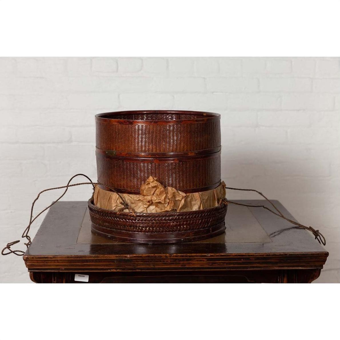 Black lacquered Chinese 19th century wooden tiered food basket with stacking parts on a wooden table indoors.