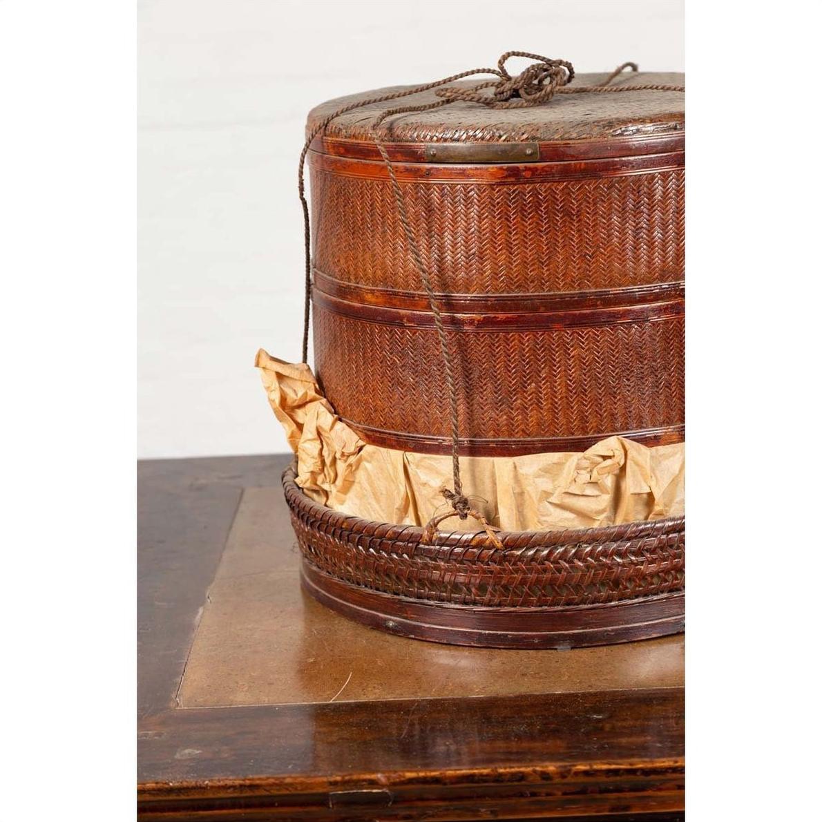 Brown wood Chinese tiered food basket with lid and string tie, 19th-century, on a wooden surface.