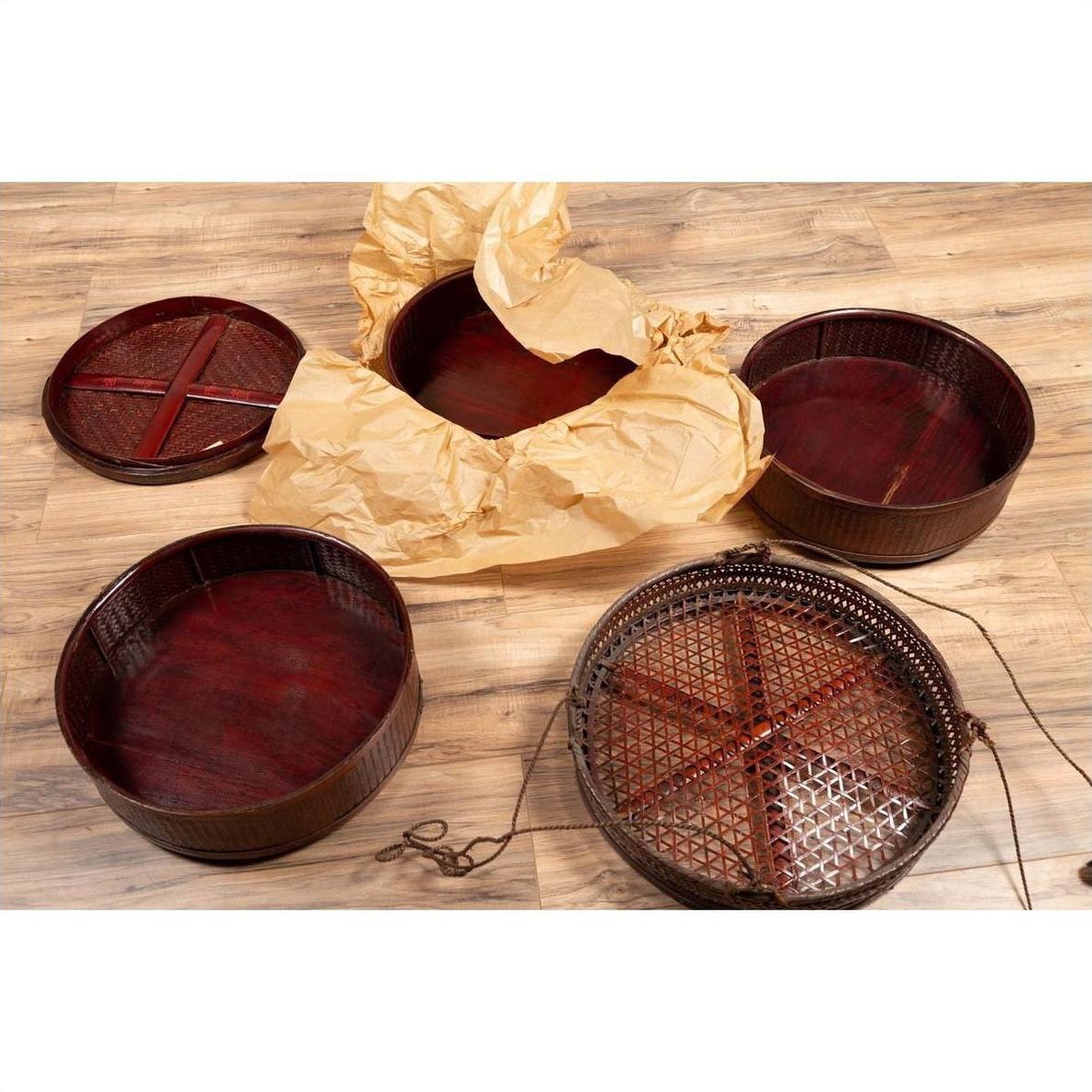 Brown wooden round baskets with stacking sections, including a Chinese tiered basket, on a wood floor indoors.