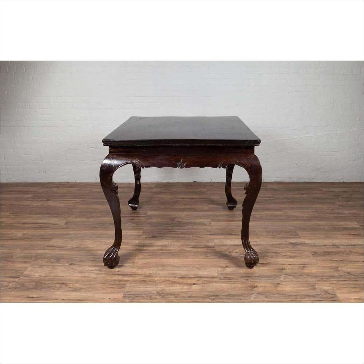 Black lacquered wood hall table with cabriole legs on wood floor against white brick wall indoors.