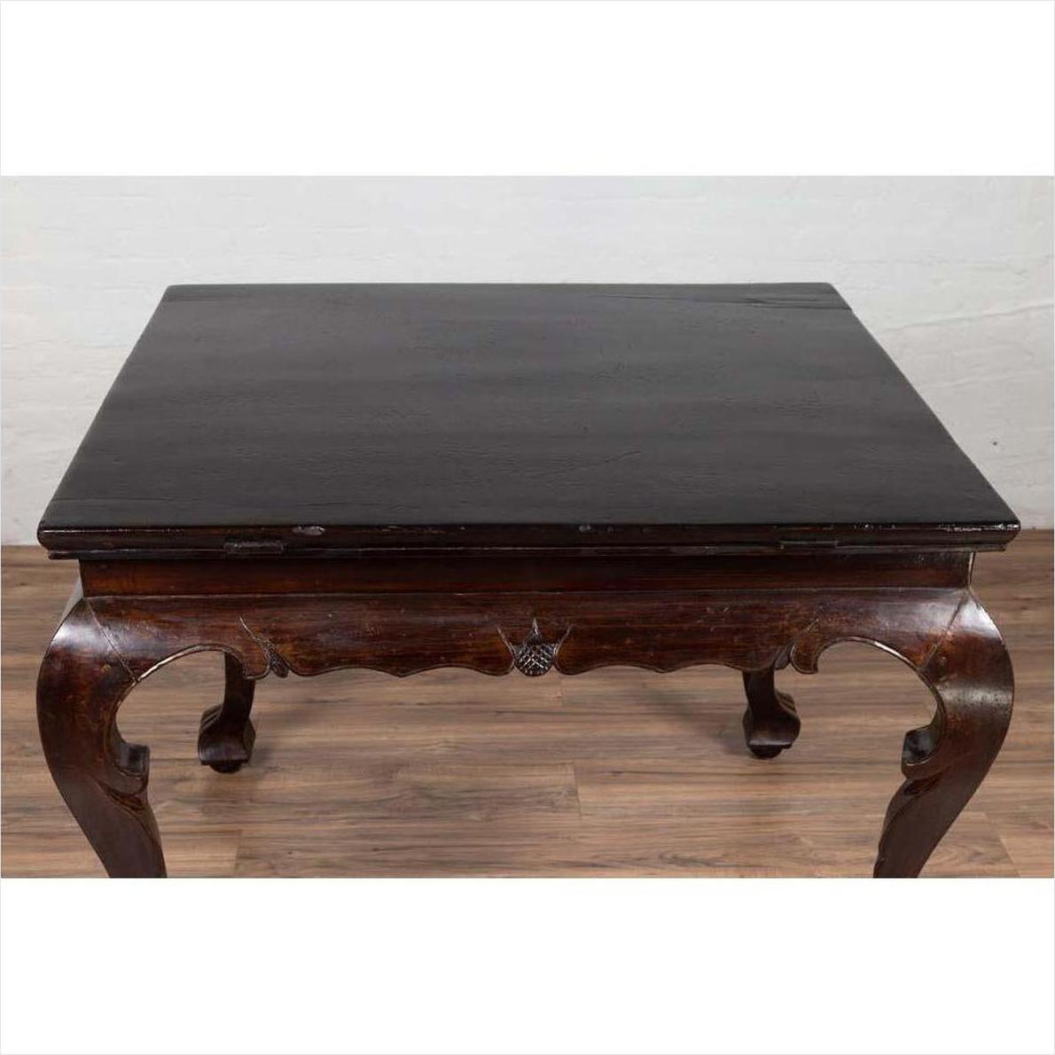 Black lacquered wood center hall table with cabriole legs on wooden floor against a white wall indoors.