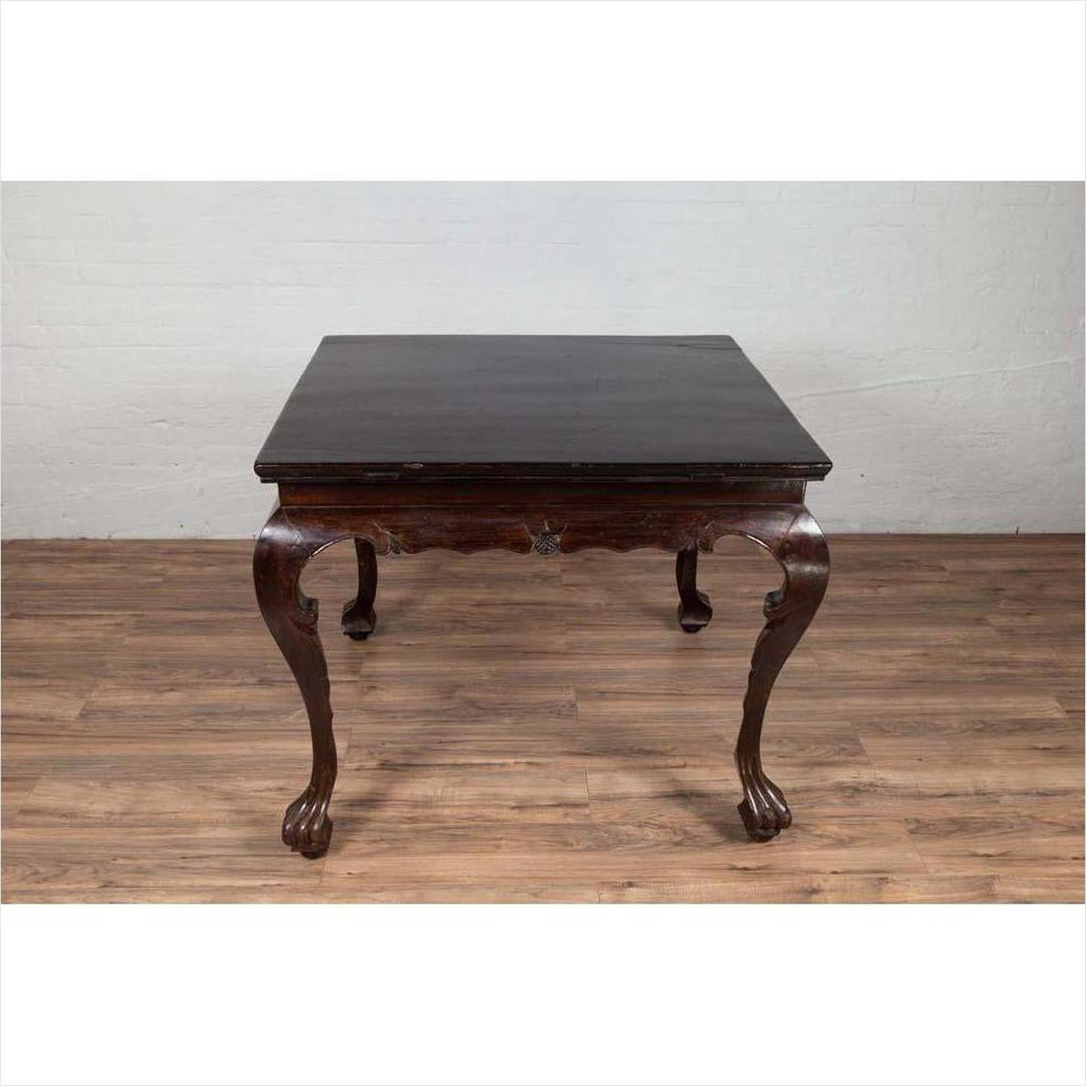 Black lacquered wood hall table with cabriole legs on wood floor against a white brick wall indoors.
