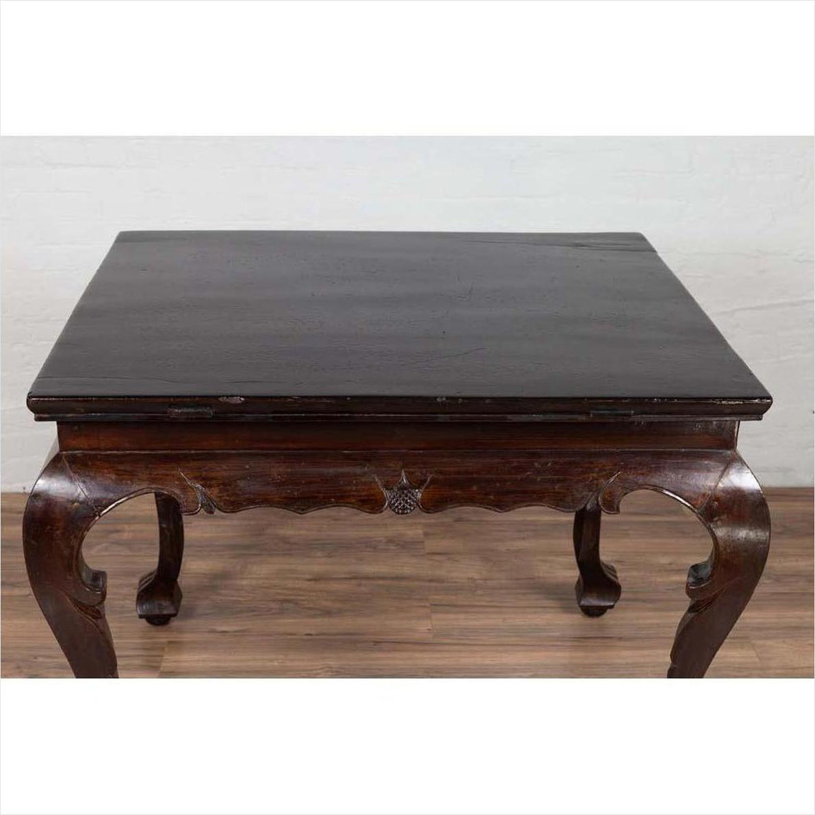 Black lacquered wood hall table with cabriole legs on wooden floor against a white brick wall indoors.