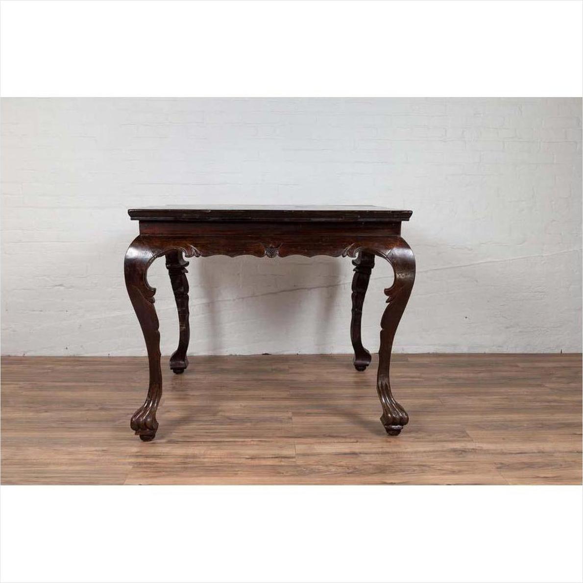 Black lacquered wood hall table with cabriole legs, positioned on a wooden floor against a white brick wall indoors.
