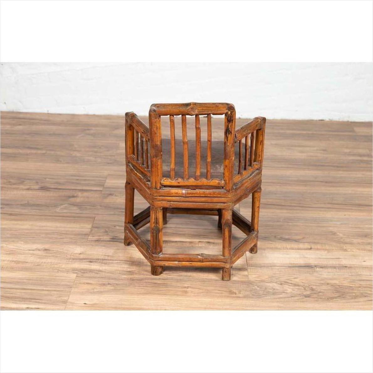 Brown bamboo frame child's corner chair with hexagonal base on wooden floor indoors.