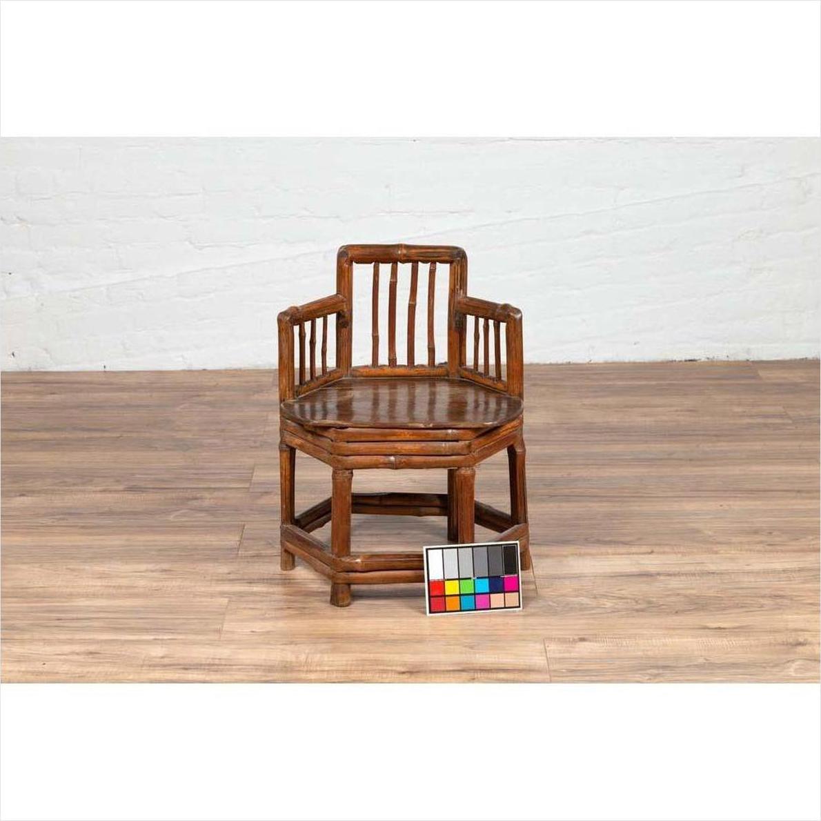Brown bamboo child's corner chair with hexagonal base on wood floor, color checker in front.